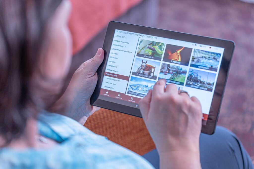 Eine Frau informiert sich auf dem Hotel-Tablet über Ausflugstipps