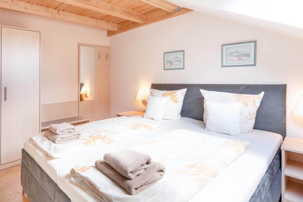 Doppelbett in modernen Grautönen unter der hellen Dachschräge mit Fenster.